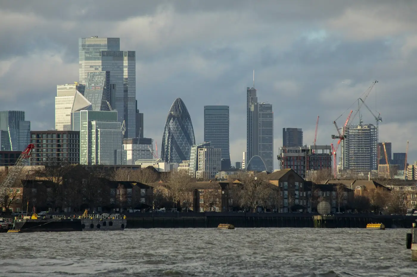 The City of London skyline seen across the Thames, with tower cranes among the office towers