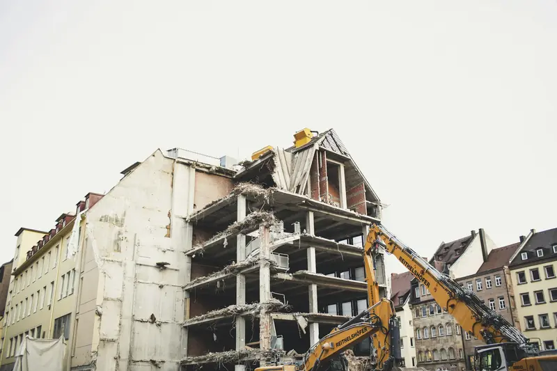 High-reach and standard excavators take down a multi-storey building between neighbouring blocks on a city street